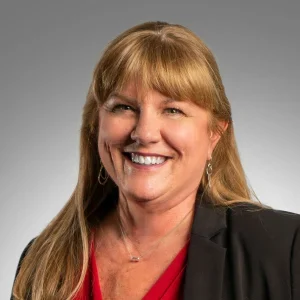 Smiling woman with long hair and blazer.